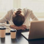 sleepy office worker at desk with multiple coffees