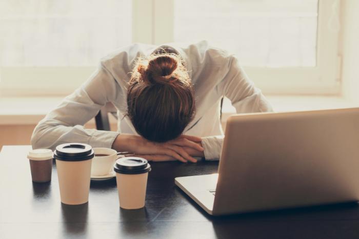 sleepy office worker at desk with multiple coffees